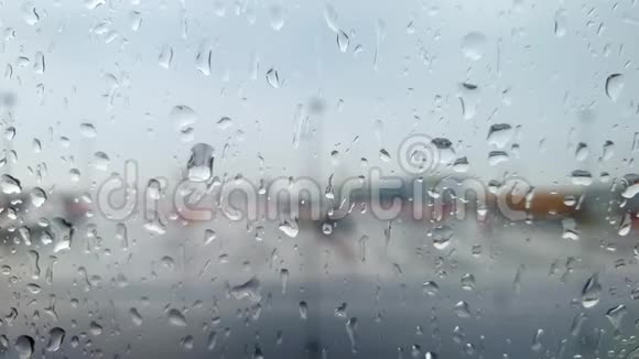 在暴雨时通过机场候机楼覆盖水滴的飞机舷窗特写4k视频视频的预览图
