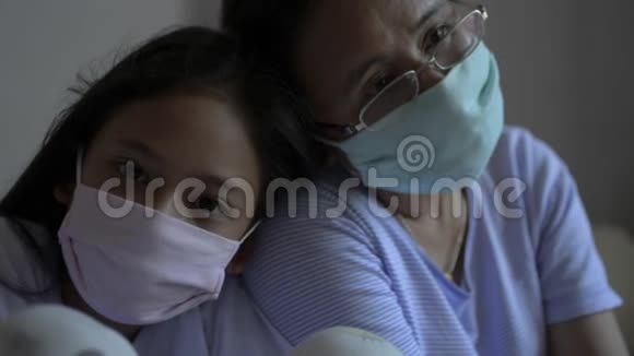 母亲和女儿戴着防护面罩以保护自己免受电晕病毒的影响并呆在家里视频的预览图