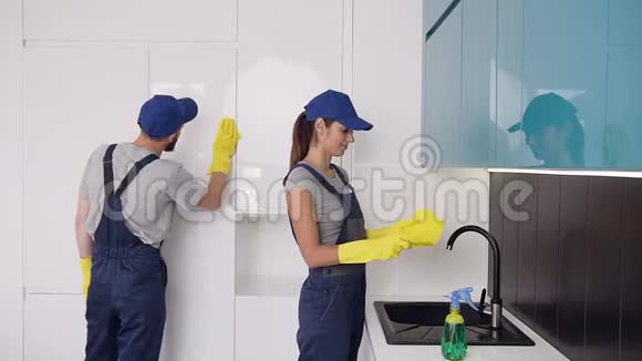 清洁公司漂亮的年轻工人戴着橡胶手套在高科技厨房里扭动着视频的预览图