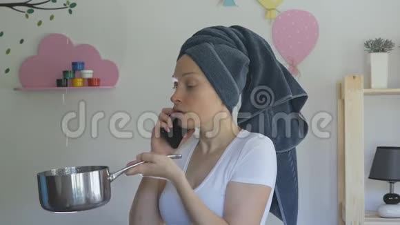 一个女人头上拿着毛巾拿着一个金属平底锅从天花板上接水在电话里说话视频的预览图