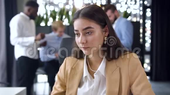 年轻有经验的年轻女商人坐在现代化的办公室里在摄像机上显示OK标志视频的预览图