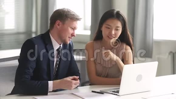 有帮助的白种人老板指着笔记本电脑教女亚洲实习生视频的预览图