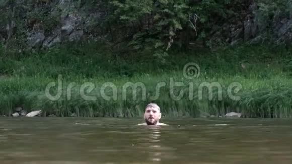 一个留着胡子的家伙在山上的背景下潜下河跳了出来夏天在大自然的水里玩洗澡视频的预览图