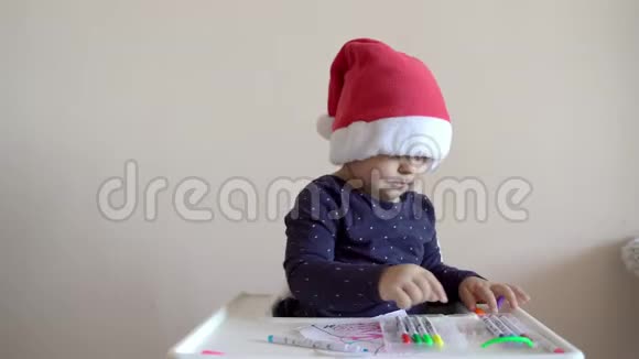 戴着圣诞帽的婴儿玩毛毡笔给一本书上色创造性活动印第安人庆祝视频的预览图