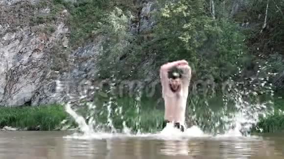 一个留着胡子的家伙在山的纹理背景下潜入水中跳了出来在大自然中游泳总金额视频的预览图