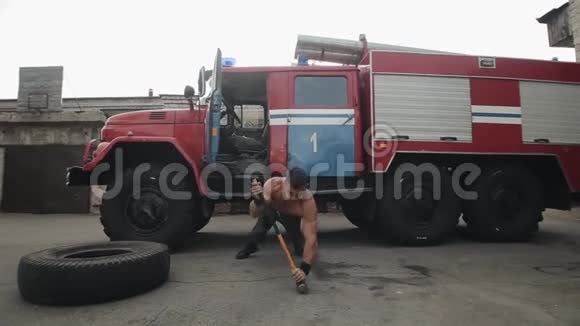 肌肉发达的英俊运动员在消防车前用大锤做俯卧撑视频的预览图