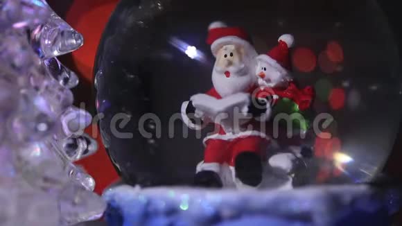 圣诞老人靠近一棵美丽五颜六色新年杉树坐在玻璃球里为孩子们准备新年礼物视频的预览图