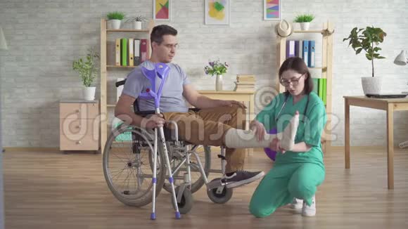 物理治疗师检查轮椅上人受伤后的腿部骨折视频的预览图