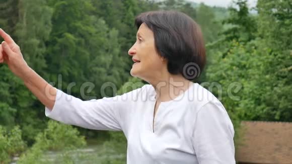 一位留着一头乌黑短发满脸皱纹的老年妇女在旅行中看到某物的户外画像视频的预览图