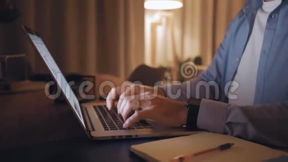 一个男人的手通过桌上的笔记本电脑输入数据的细节视频的预览图