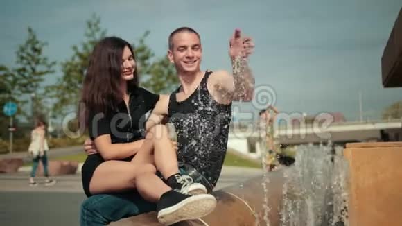 恋爱中的夫妻坐在喷泉旁的女孩和男人微笑着快乐着视频的预览图