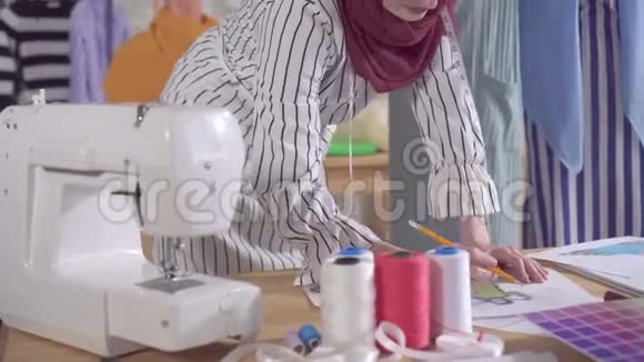 年轻的穆斯林女性时装设计师在一个现代化的工作室里工作视频的预览图