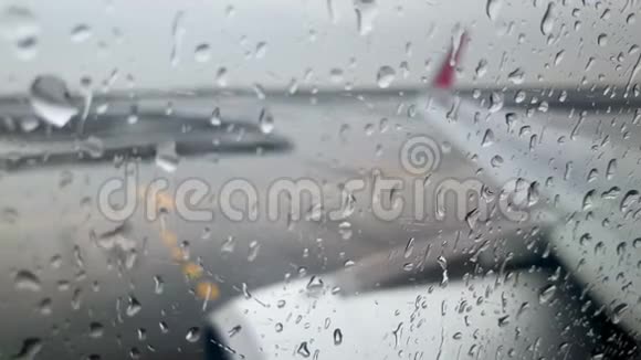强雨时飞机机翼和发动机在机场跑道上驾驶的4k视频视频的预览图