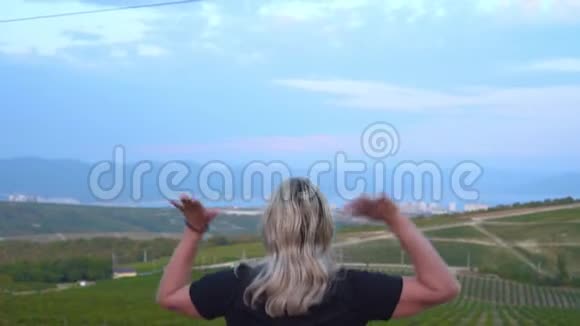 一个女人走在葡萄园的高处站着举起双手快乐地蹦蹦跳跳视频的预览图