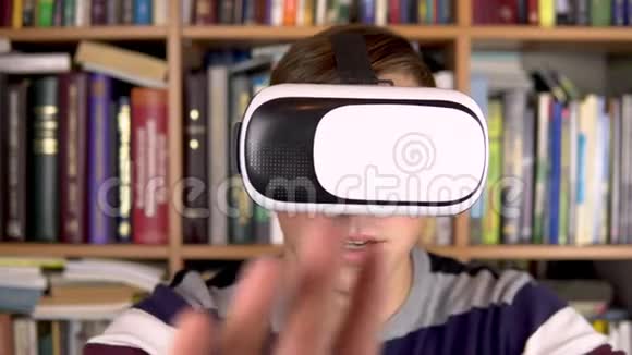图书馆里戴VR眼镜的年轻人一个头戴VR头盔的人在检查和触摸虚拟现实在里面视频的预览图