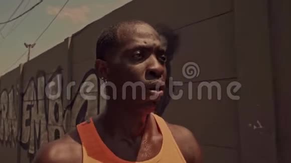 精疲力竭的黑人非洲美国职业跑步运动员在城市跑步后步行降温擦去汗水视频的预览图