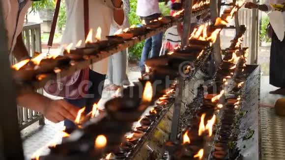 4k佛教崇拜者的视频在佛寺祭坛上点燃并点燃燃烧的油灯视频的预览图