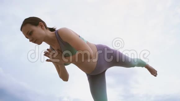 年轻的孕妇在户外做瑜伽站在一条腿上视频的预览图