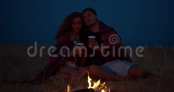 一对浪漫的情侣晚上围坐在篝火旁视频的预览图