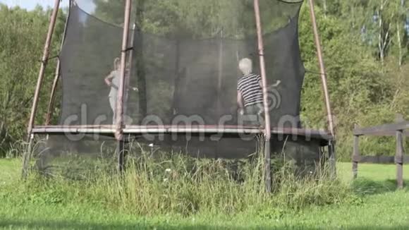 夏天一个男孩和一个小女孩在小屋的蹦床上跳视频的预览图
