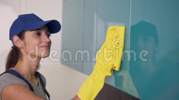 漂亮苗条的女士穿着工作服戴着橡胶手套用黄色擦拭厨房家具视频的预览图