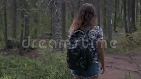 带背包的女旅行者穿过树林背面视频的预览图