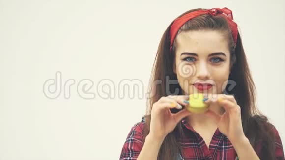 漂亮的年轻时尚女孩拿着黄色美味的马卡龙在她的嘴前扬起眉毛视频的预览图
