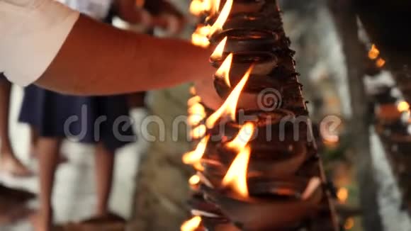 4k斯里兰卡佛教寺庙内朝拜者点燃燃油灯的特写视频视频的预览图