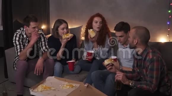 白种人快乐的男人和女人正在吃奶酪披萨在公寓里的室内聚会上聊天放松视频的预览图