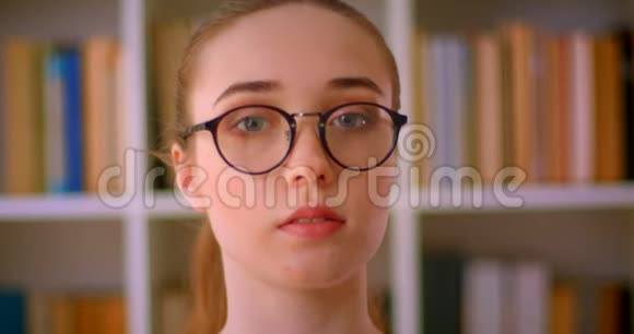 年轻漂亮的红头发女学生戴着眼镜在室内看着图书馆里的摄像机视频的预览图