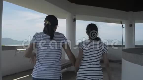 母亲和女儿穿着休闲装正冲进观景塔欣赏海湾上空令人叹为观止的景色视频的预览图