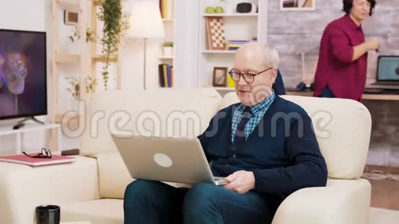 一对年长夫妇戴着眼镜坐在沙发上在笔记本电脑上打视频电话视频的预览图