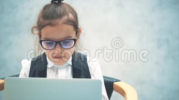 一个小女老板坐在椅子上拿着笔记本电脑灰色背景特写看笔记本电脑视频的预览图