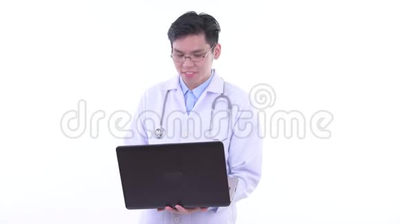 快乐的亚洲青年医生一边说一边用笔记本电脑视频的预览图
