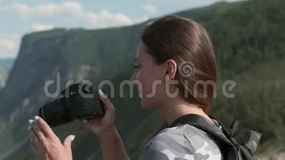 女旅行者站在山顶时用相机拍摄美丽的照片特写视频的预览图