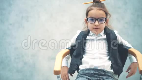 灰色背景的小商业女孩在这悲伤的坐在椅子上说话表现各种手势服装视频的预览图