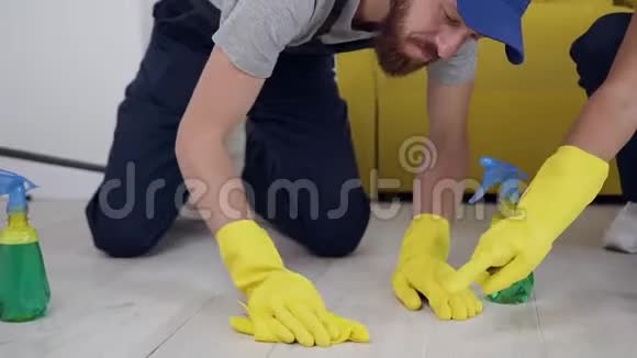 专注的清洁服务的男人和女人用抹布擦拭地板视频的预览图