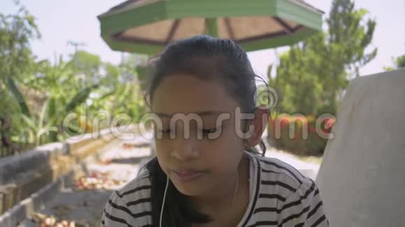 肖像可爱的亚洲女孩戴着耳机吃着家在公共公园快乐地制作冰淇淋视频的预览图