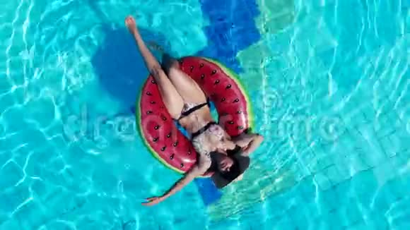 年轻女子躺在酒店游泳池的橡胶圈上视频的预览图