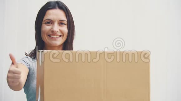 漂亮的年轻女人拿着大纸箱伸出拇指微笑着视频的预览图