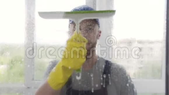 专注的年轻男洗手机用一把拖把轻擦湿窗户视频的预览图