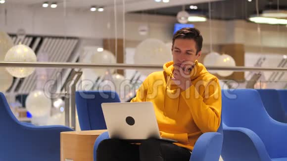 年轻自信的忙碌的男人坐在咖啡馆里用笔记本电脑工作视频的预览图