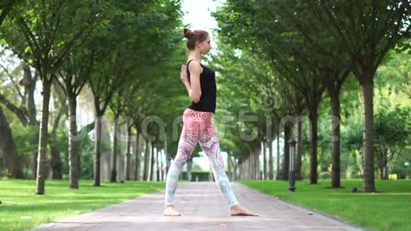 一个苗条的运动女孩在公园里慢动作练习瑜伽视频的预览图