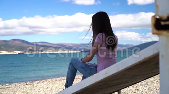 年轻而迷人的女孩靠在海滩上慢镜头地看着镜头视频的预览图