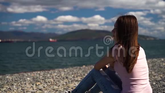 坐在海滩上看着大海的年轻女孩心烦意乱女孩和男朋友分手了现在视频的预览图
