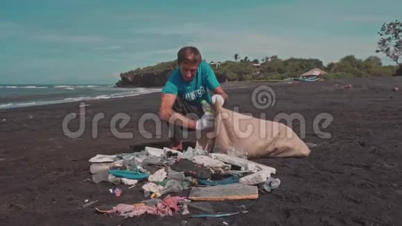 志愿者在海洋海滩上分类垃圾在生态袋中折叠塑料瓶视频的预览图