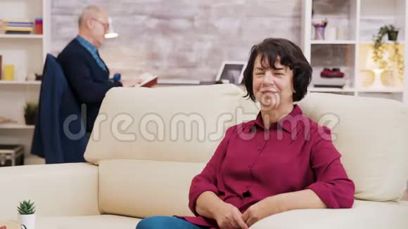 老年妇女坐在沙发上戴眼镜的肖像视频的预览图