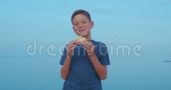 这个男孩正在户外吃披萨带着美味披萨的微笑男孩视频的预览图