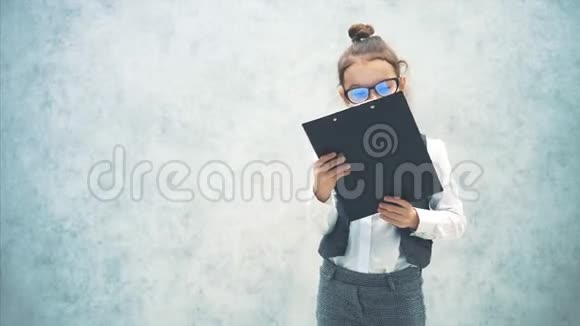 这个聪明的女孩是灰色背景并保留一个文件夹与铭文业务灰色背景特写镜头视频的预览图