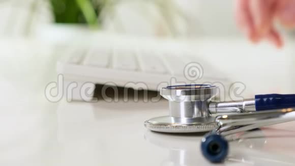 在工作场所工作的医生诊所工作人员在笔记本电脑上打字前景上的听诊器快关门视频的预览图